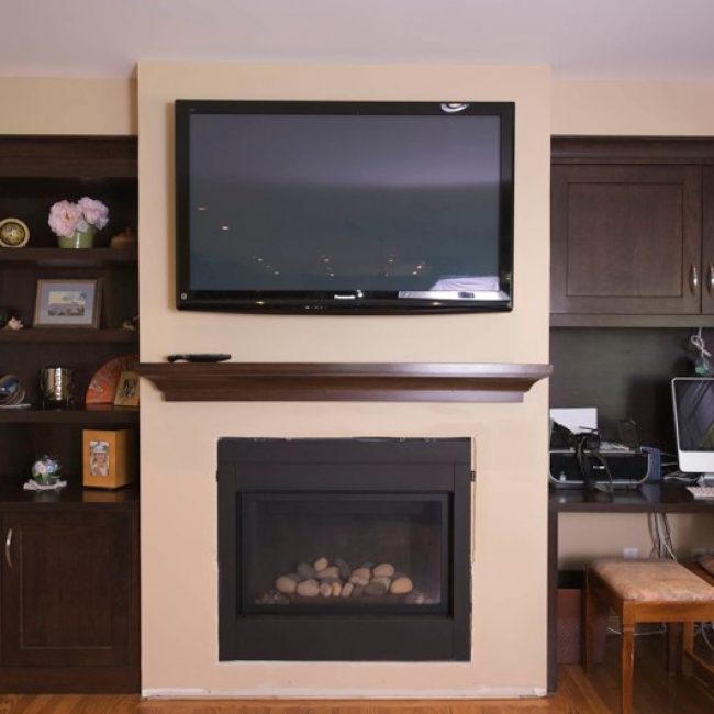 Talk about a world of difference! We made these beautiful dark brown custom cabinets in a shaker style, complete with shelves and a built-in desk. The matching mantle adds a perfect finishing touch.