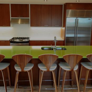 Kitchen island with stunning green countertop and modern stainless steel sink and faucet by Evolve Kitchens